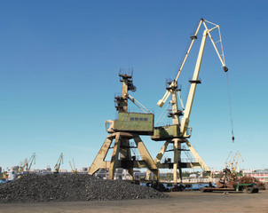 Cranes and charcoal in port with blue sky background