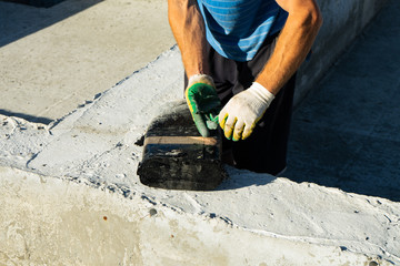 Workers carry out waterproofing of the Foundation for the construction of a wooden house.