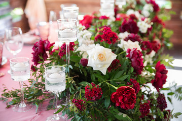 Decorated area in gold and burgundy colors with white candles and flowers