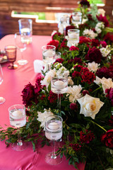 Decorated area in green and burgundy colors with white candles and flowers