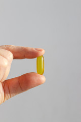 Woman Fingers Holding Yellow Capsule Vitamin