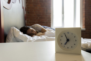 Young girls sleeps in the morning in bed with alarm