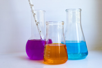 Three cones with colored chemicals liquid close up