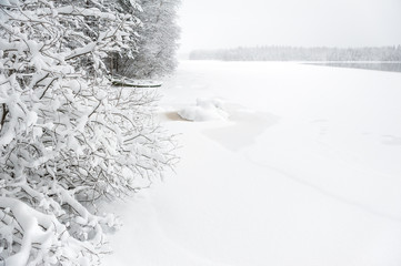 Winter landscape along snow covered riverbank in Finland.