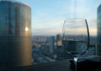 Wineglass on table with aerial cityscape at sunset on the background. Concept of luxury leisure. Shallow focus