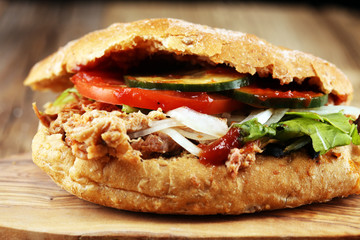 Pulled pork sandwiches with BBQ sauce, cabbage and pickles on wooden table