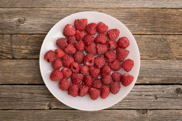 Plate with raspberry on wooden table