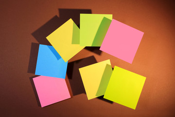 Kolorowe, kwadratowe kartki z cieniem na brązowym kartonie. © Stanisław Błachowicz