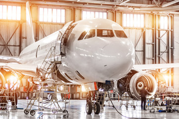 Naklejka premium Pasażerski samolot komercyjny na utrzymanie silnika turbo jet i napraw kadłuba w hangarze lotniskowym. Samoloty z otwartym kapturem na nosie i silnikach oraz bagażnikiem.