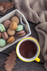 A cup of hot cocoa, macaroons, a knitted sweater on a wooden table. Autumn. Winter. Cozy.