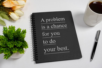 Notebook with wisdom quote and coffee cup on white background.