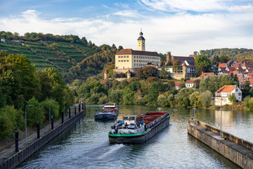 Zwei Transportschiffe auf dem Neckar kreuzen sich vor der Schleuse Gundelsheim. Im Hintergrund Weinberge und Schloss Horneck