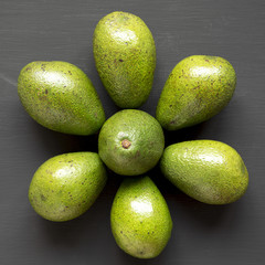 Whole avocados on black background, top view. From above, flat lay.