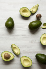 Whole and chopped avocados on white wooden background, overhead view. Top view, from above.