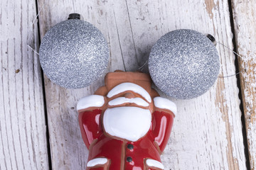 Nikolaus und Weihnachtsmann mit silbernen Christbaumkugeln auf einem rustikalen weißen Holz...
