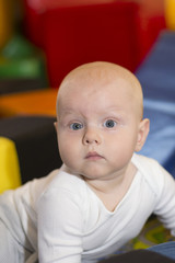Baby boy sits on the floor with soft cubes in the playroom