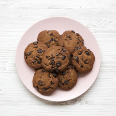Chocolate chip cookies on a pink plate on a white wooden background. Flat lay, overhead, top view.