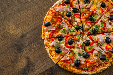 slices of Pizza with Mozzarella cheese, ham, pepper, meat, Tomatoes, olives, Spices and Fresh Basil. Italian pizza on wooden background