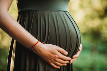 detail of pregnant belly expecting mother in green dress