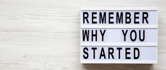 Lightbox with 'Remember why you started' words over white wooden background, overhead. Copy space.