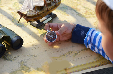 Boy in the image traveler studying his map of travel and adventure in nature. old ship sailboat on an old vintage map, an infamous pipe, a Columbus day concept. sailor.