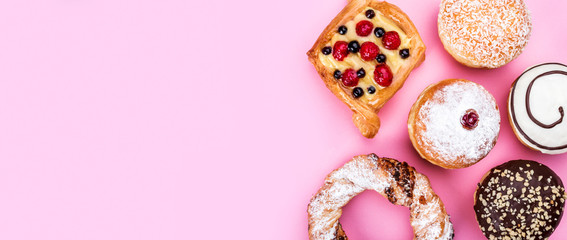 Assortment of sweet cakes and donuts with chocolate cream on pink background, top view and copy space