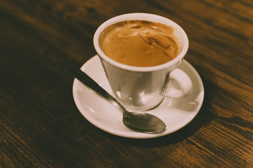 White cup of freshly made coffee on a wooden rustic table.
