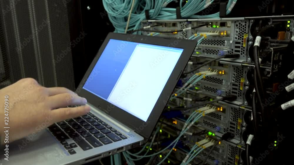 Poster engineer in the server room with a laptop on the background of an optical server with flashing light