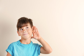 Cute little boy with hearing problem on light background. Space for text