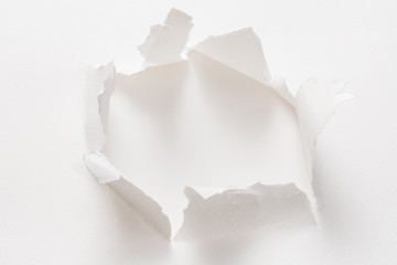 ripped torn white paper showing empty space. hole with rough edges. minimalistic background for...