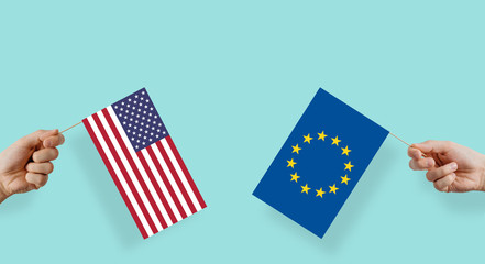 The flags of the United States and the European Union are kept in their hands. The hand raises the...