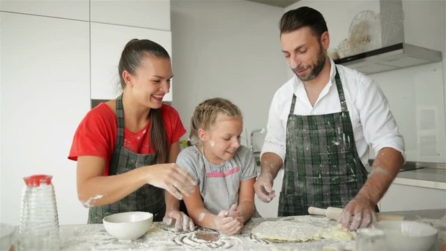 Parents with Caucasian Appearance Are Having Fun With Their Daughter While Cooking. It Looks So Funny. Good Mood