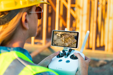 Female Unmanned Aircraft System (UAV) Quadcopter Drone Pilot with Controller Inspecting New House...
