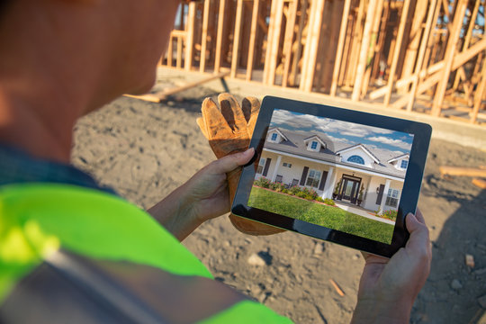 Female Construction Worker Reviewing House Photo on Computer Pad at Construction Site