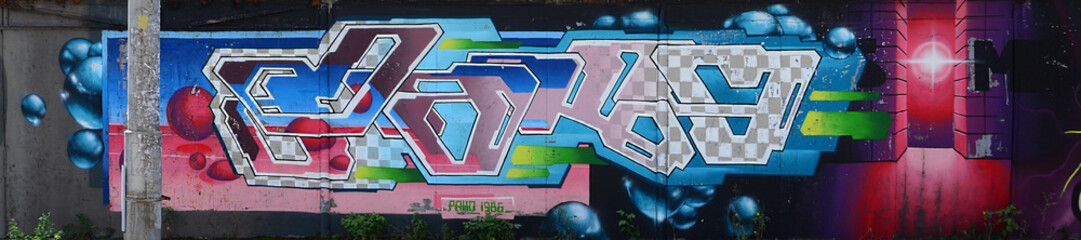 Fragment of graffiti drawings. The old wall decorated with paint stains in the style of street art culture. Multicolored background texture