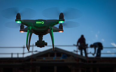 Silhouette of Unmanned Aircraft System (UAV) Quadcopter Drone In The Air at Construction Site