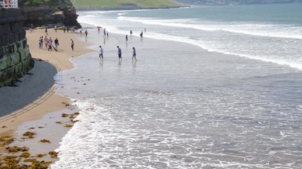 Families paddling in the sea on a hot day in Whitby.