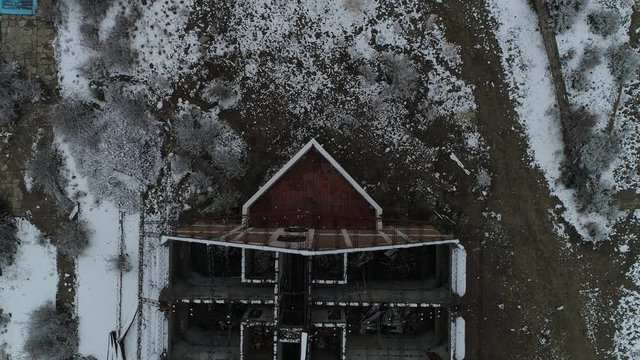 Aerial senital drone scene of destroyed building, old burned hotel in snowy day. General view of metal structure of construction and top view of rooms distribution. Camera moves along lost hotel