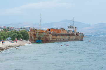 Shipwreck on a beach. Tourists swimming. Adriatic Sea.