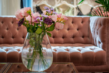 A bouquet of roses in a vase on a glass table. Modern, stylish interior. Sofa on the background. Oslo, Norway