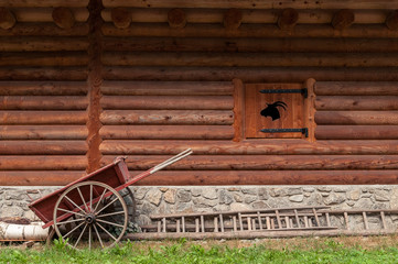 Obraz premium Wall of mountain cabin in wood with inlaid wooden box, a wooden wheelbarrow and a wooden staircase