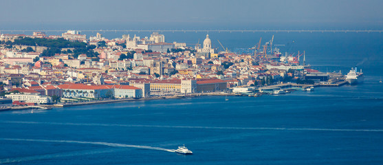 Obraz premium Beautiful super wide-angle panoramic aerial view of Lisbon, Portugal with harbor and skyline scenery beyond the city, shot from belvedere observation deck of Cristo Rei