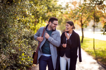 Businessman and businesswoman walking in a park and discussing