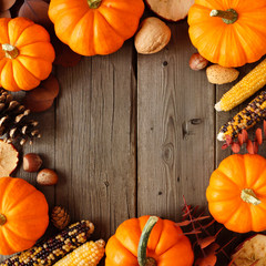 Autumn square frame of pumpkins and fall decor on a rustic wood background with copy space