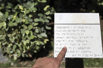 Blind reading text caption in braille language at garden