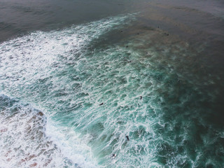 View of Praia do Guincho, Guincho beach, a popular Atlantic Ocean beach on Portugal's Estoril coast, municipality of Cascais, with surfers surfing on the waves, shot from drone