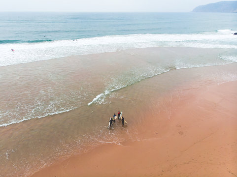 View of Praia do Guincho, Guincho beach, a popular Atlantic Ocean beach on Portugal's Estoril coast, municipality of Cascais, with surfers surfing on the waves, shot from drone