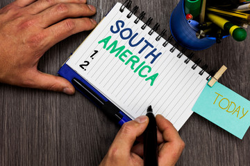 Conceptual hand writing showing South America. Business photo showcasing Continent in Western Hemisphere Latinos known for Carnivals Man holding marker notebook reminder cup markers wood table