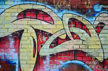 Fragment of graffiti drawings. The old wall decorated with paint stains in the style of street art culture. Colored background texture in warm tones