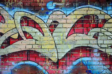 Fragment of graffiti drawings. The old wall decorated with paint stains in the style of street art culture. Colored background texture in warm tones